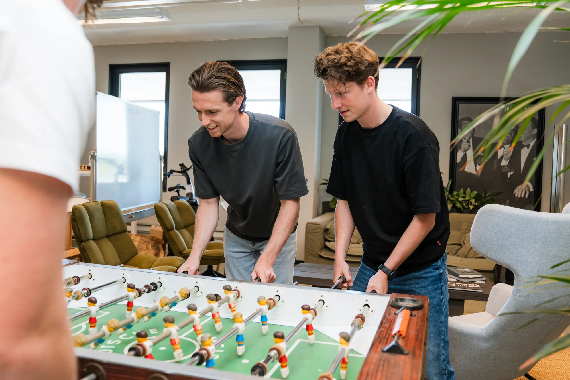 Teamleden spelen tafelvoetbal in het kantoor van AI Collega's