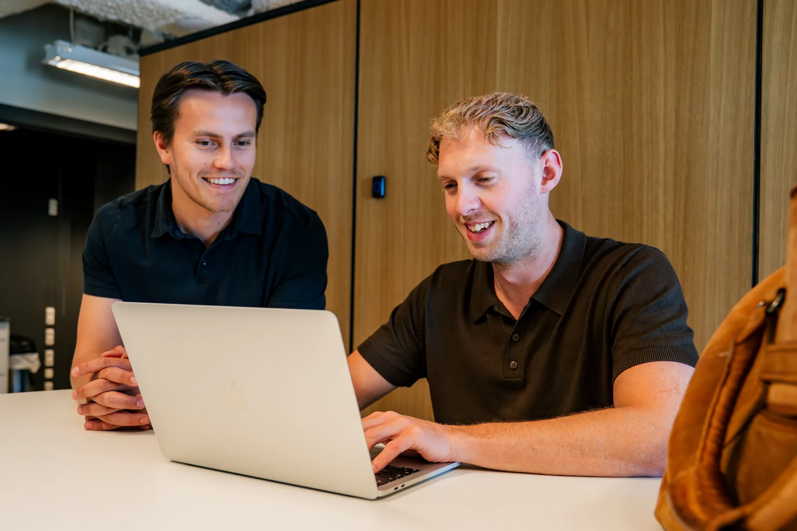 Twee collega's werken samen aan een laptop